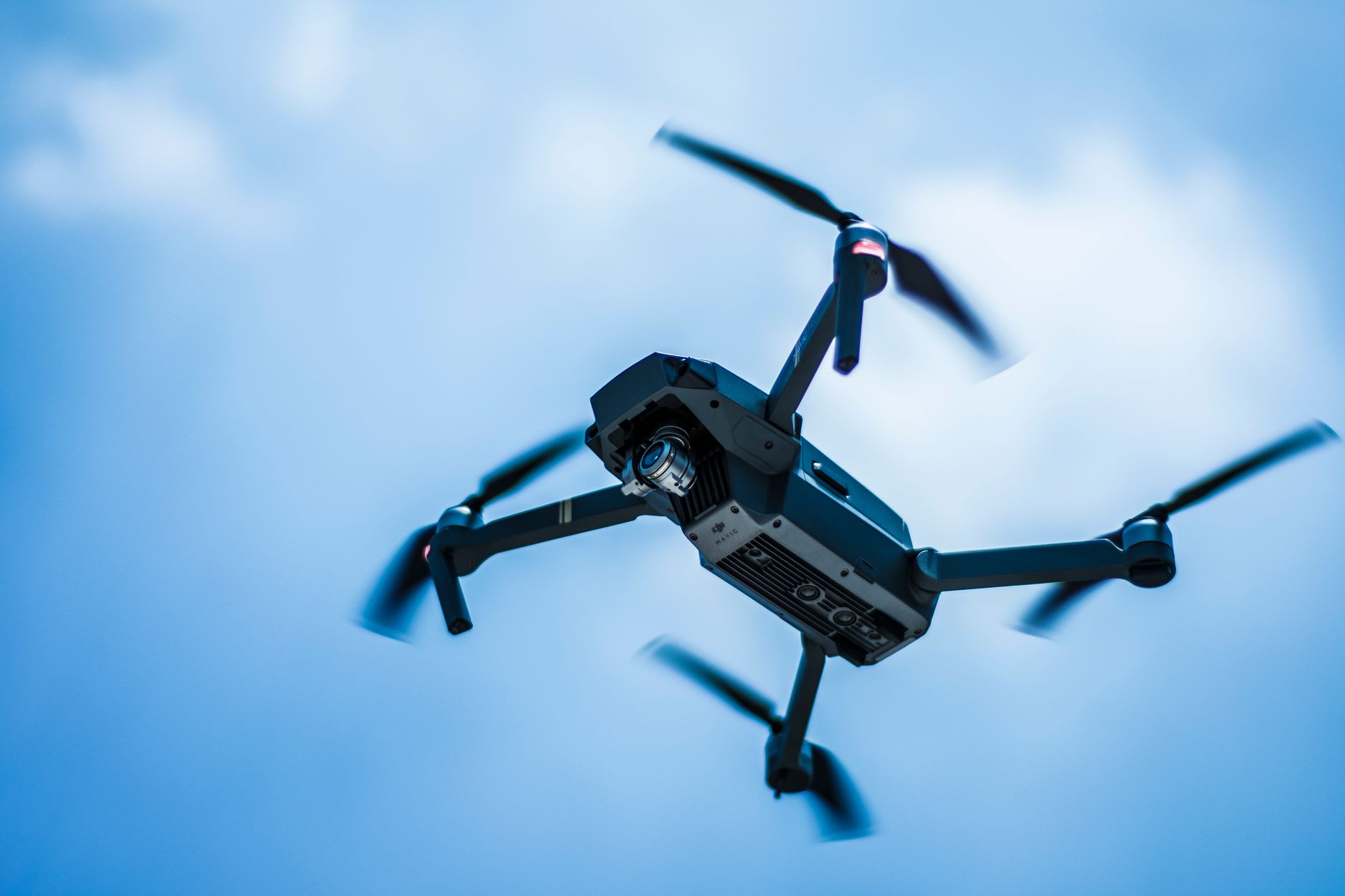 Small drone hovering at eye level in an open park