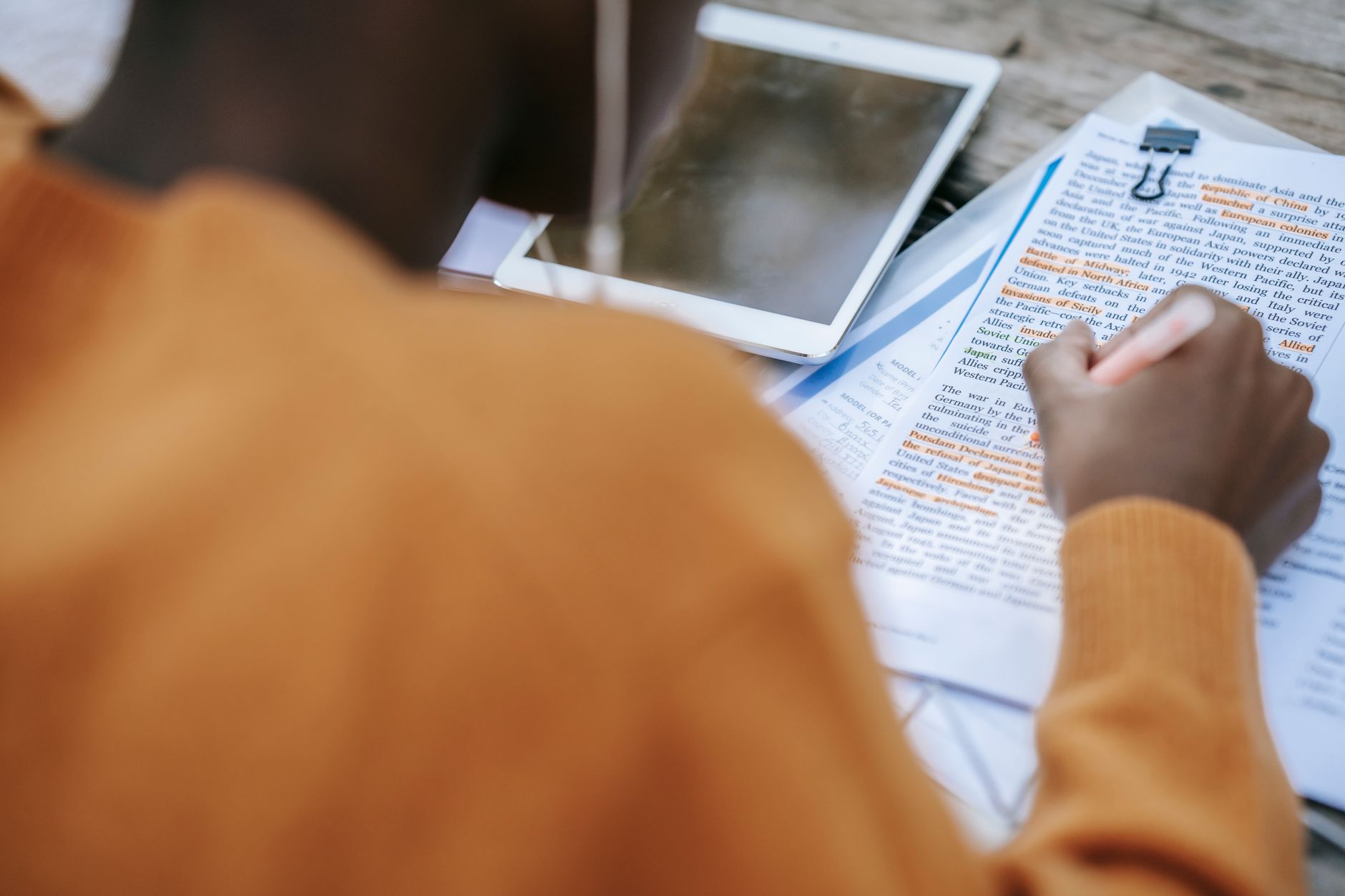Person studying a drone license test book with a small drone nearby.